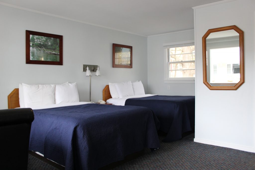 2 beds in hotel room with mirror on wall